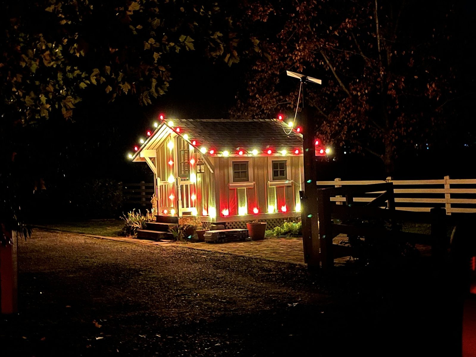 Small playhouse outlined in alternating red and white C9 bulbs at night