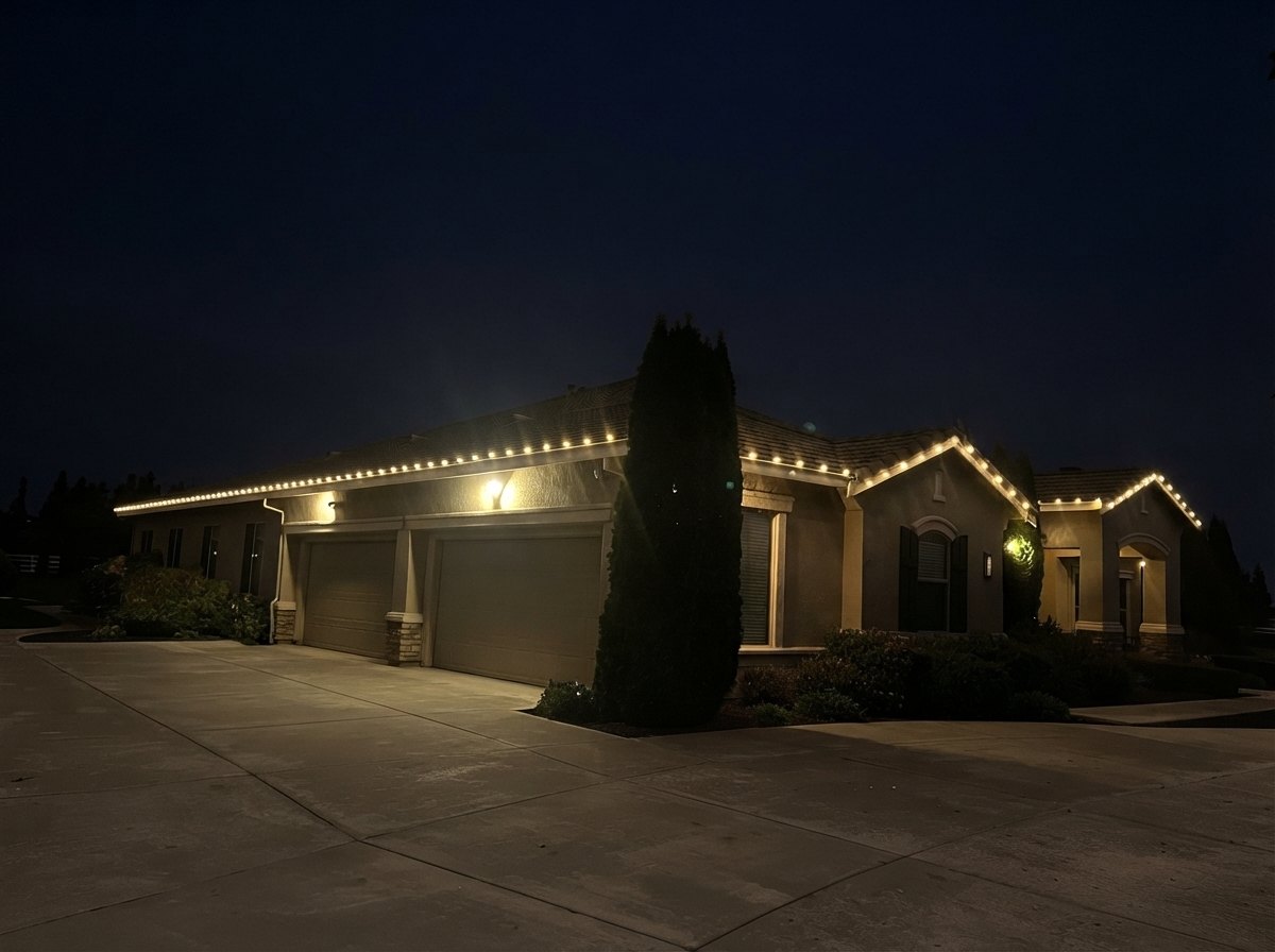 Single-story stucco home with C9 lights along the full roofline and front gables at night